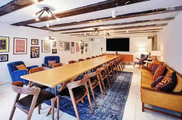 Living Room at The Hoxton, Amsterdam: stylish meeting space with wooden table and cozy seating.