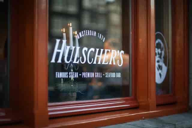 Hulscher's restaurant window, featuring elegant steak and seafood dining for private events.