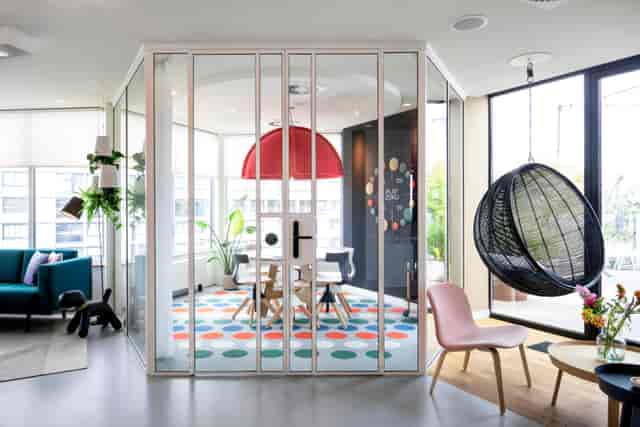 Modern meeting room in Zoku Amsterdam with glass walls for creative collaboration.