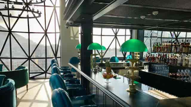 Stylish bar at The Silo Hotel with green lamps, ideal for networking events and gatherings.