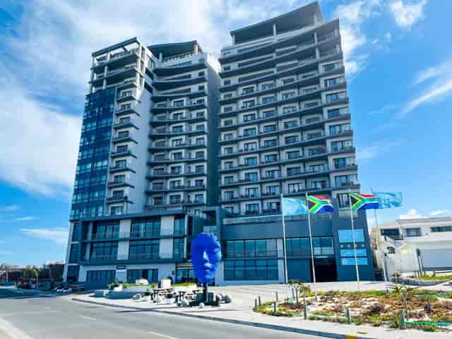 Modern Blaauwberg Beach Hotel with glass windows and blue art, perfect for events.