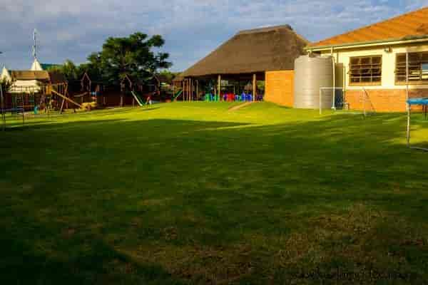 Spacious outdoor event venue with thatched roof and lush green lawn in Kyalami.