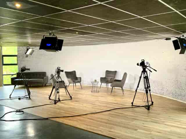 Small studio with soft seating for hybrid events, perfect for interviews and panel discussions.
