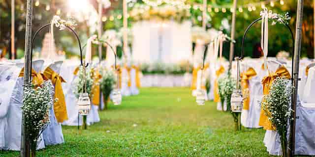 Romantic outdoor wedding setup with white chairs and lush greenery in Zen Garden.