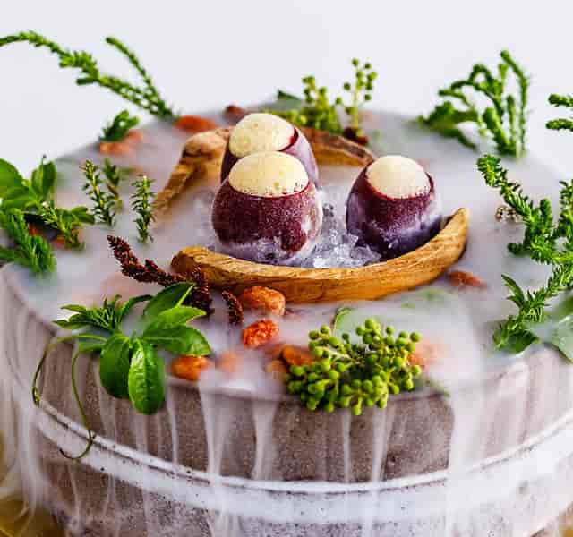 Elegant culinary display with smoke and greenery for upscale receptions and gala dinners.