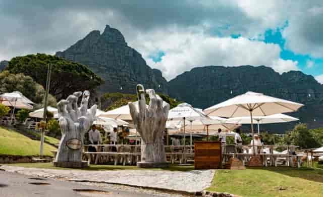 "Outdoor restaurant event space with oversized hand sculptures and mountain views in The Lawns."