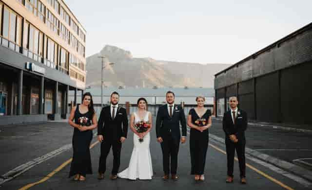 Bridal party in elegant attire at Colorbox Studios outdoor courtyard with mountain backdrop.