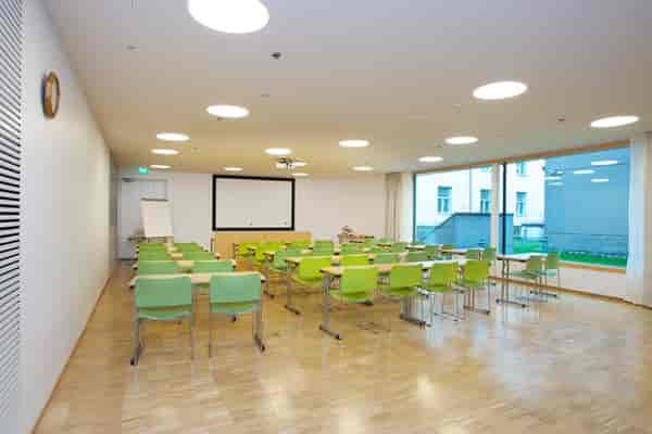 Bright meeting room with green chairs, ideal for workshops and training sessions.