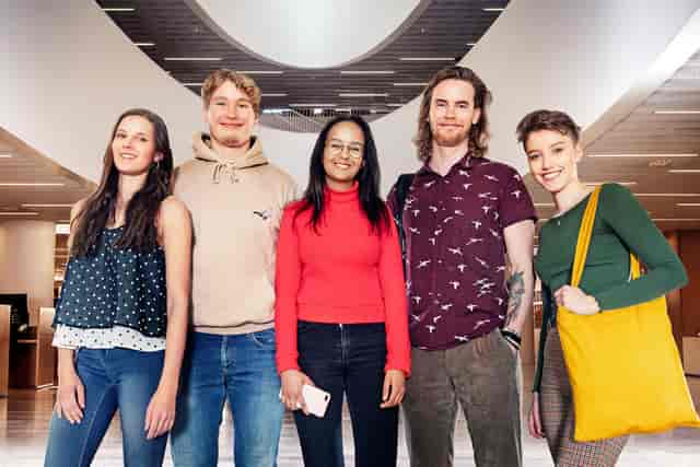 Diverse young adults collaborating in modern University of Helsinki study space for workshops.