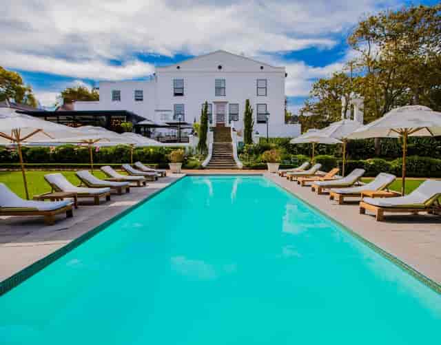 Alphen Boutique Hotel garden poolside with lush landscaping, ideal for outdoor events.