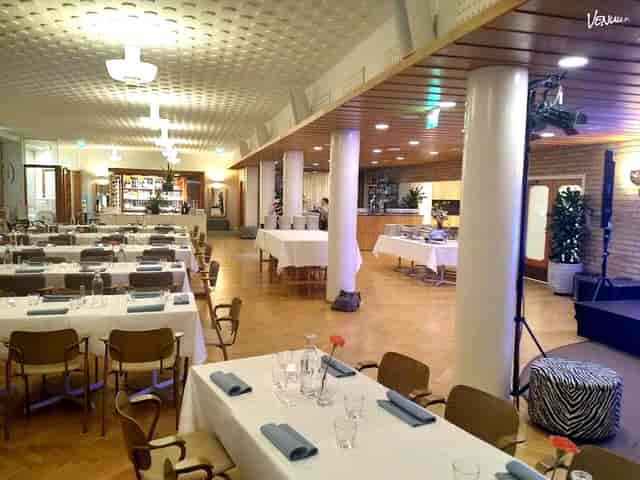 Spacious event venue with arranged tables for dining, ideal for corporate and social events.