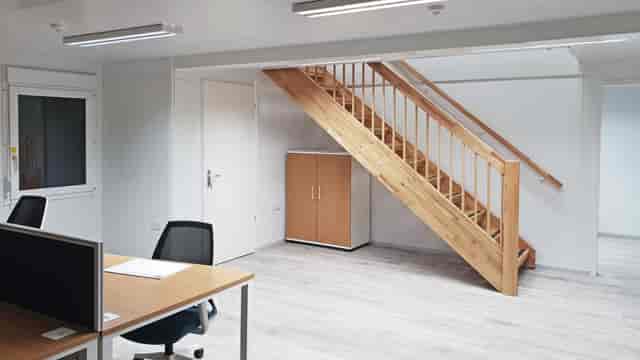 Modern minimalist office in HUONE Helsinki with wooden staircase, perfect for workshops.