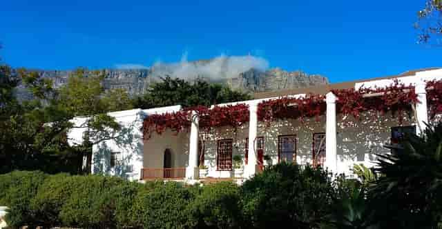 Elegant gallery venue with lush greenery and mountain backdrop for weddings or corporate events.