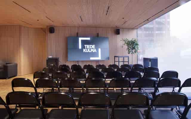Modern event space with black chairs and screen, perfect for presentations and meetings.