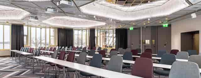 Modern Hilton Helsinki Strand ballroom for conferences with stylish furnishings and natural light.