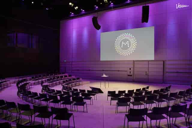 "Modern Musiikkitalo event space with purple lighting for impactful presentations and meetings."