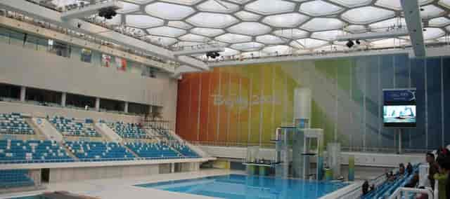 Modern Water Cube arena with hexagonal ceiling for swimming and entertainment events.