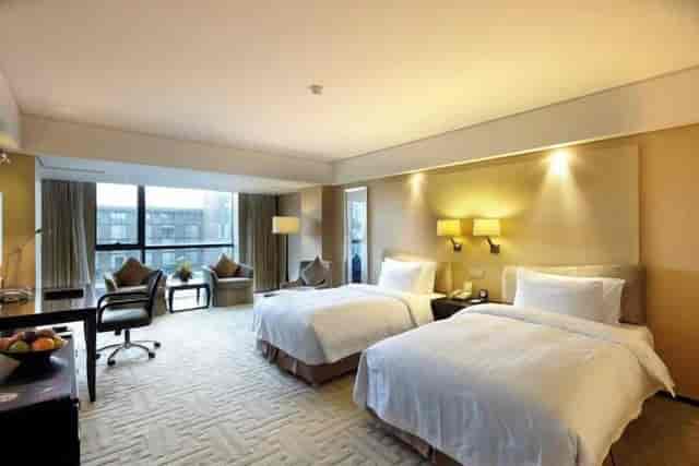 "Modern hotel suite with two beds, ideal for business travel and meetings."