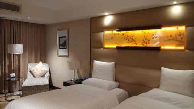 Twin beds in a stylish hotel room at Gehua New Century Hotel Beijing for business travelers.