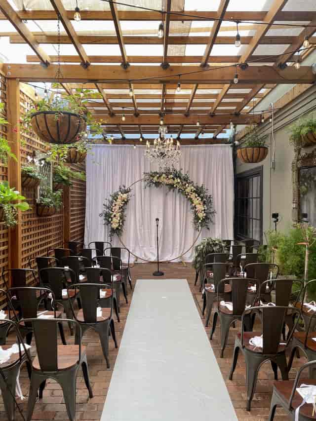 Elegant outdoor wedding setup with floral arch and stylish lighting at Angelicas patio.