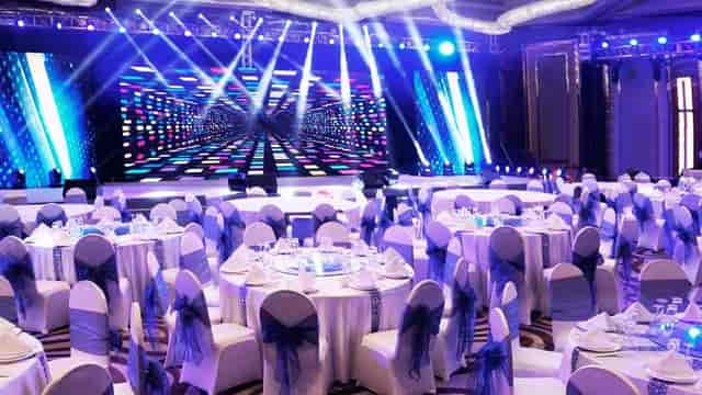 "Elegant Kunlun Ballroom banquet hall with white linens and blue sashes for conferences."