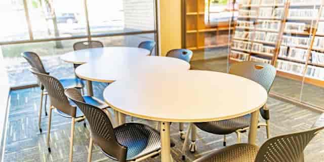 Well-lit meeting room with white tables and ergonomic chairs for productive collaboration.