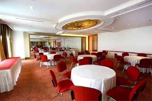 Meeting room in The Bellezza Suites with round tables and red chairs, ideal for events.