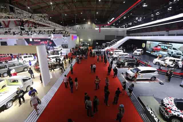 "Jakarta International Expo automotive exhibition with vintage and modern vehicles on red carpet."