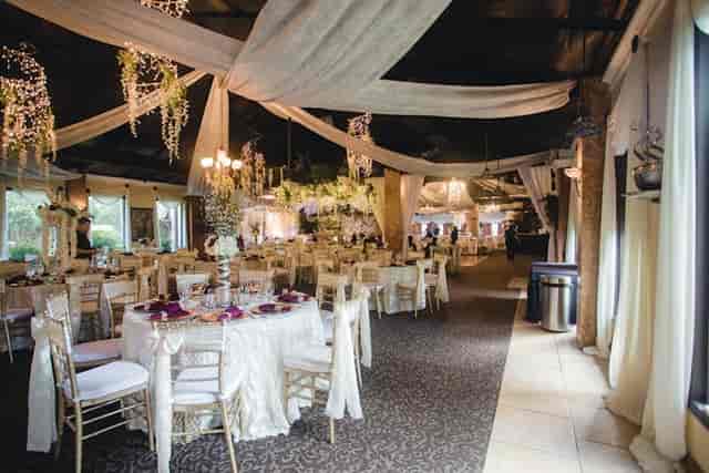 Elegant corporate event venue with draped fabric and floral arrangements for weddings.