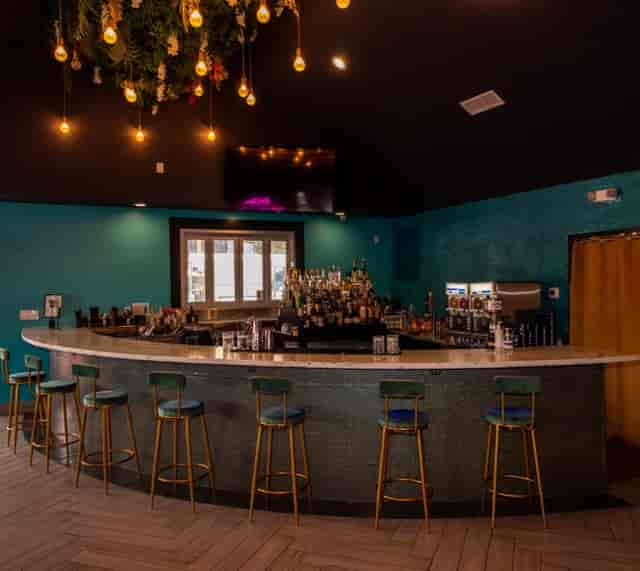 Stylish bar at Heights House Hotel with teal backdrop, perfect for cocktail receptions.