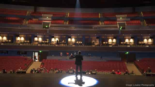Speaker in spotlight at Smart Financial Centre theatre during an event.
