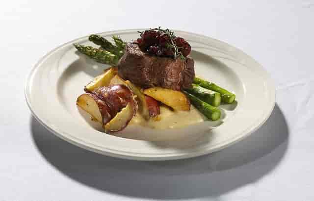 Plated beef dish with berry sauce, perfect for events and catering at The Pinnacle Center.