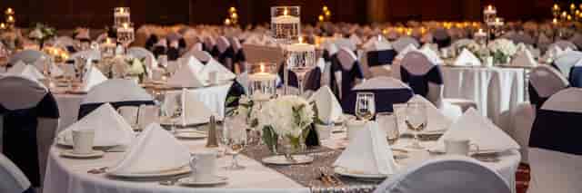 Elegant ballroom with white tables, ideal for weddings and corporate events.