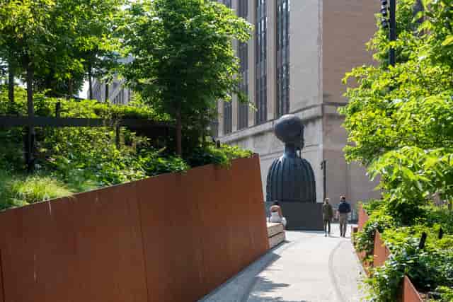 Urban pathway with greenery and art installation, perfect for outdoor networking events.
