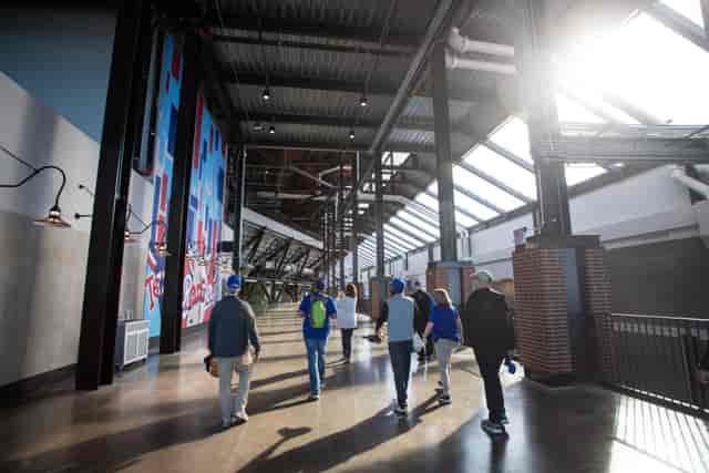 Attendees walking through Globe Life Field's modern, well-lit concourse for event networking.
