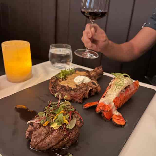 Elegant dining setup at Alexander's Steakhouse with steak and lobster for corporate events.