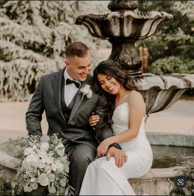 Joyful couple at wedding with elegant fountain backdrop, ideal for events and photography.