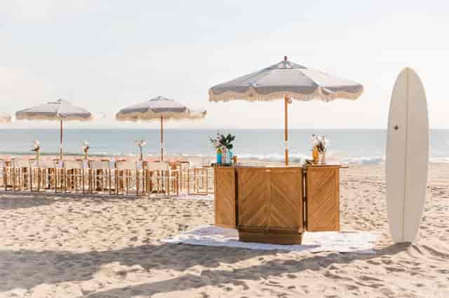 Beachside wedding event setup with elegant tables and stylish bar in Bliss Beach.