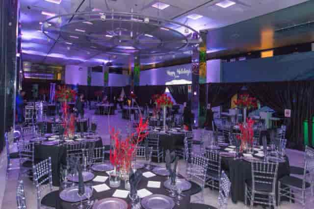 Elegant function room with round tables and purple lighting for corporate events or galas.