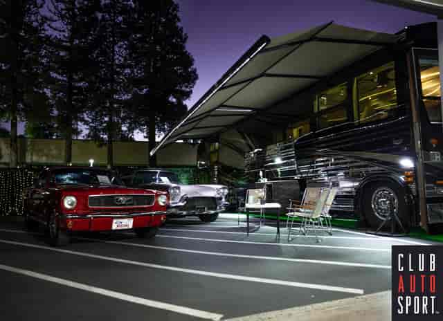 Stylish outdoor event at Club Auto Sport with vintage car display and luxury motorhome.