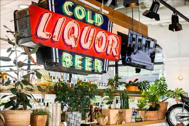 Vibrant bar area at FlavorHook Dallas with neon sign, perfect for social events and gatherings.
