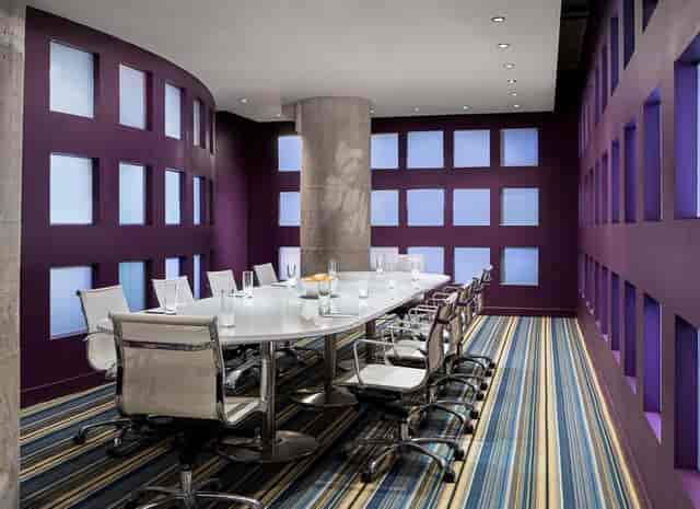 Modern conference room in Aloft Dallas, featuring vibrant purple walls and natural light.