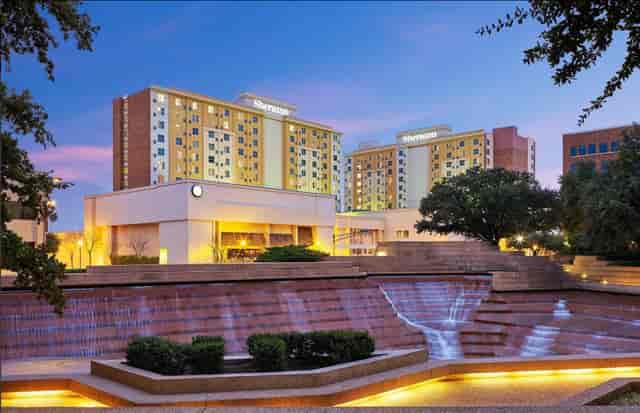 Suites at Sheraton Fort Worth Hotel with modern architecture and serene water feature.