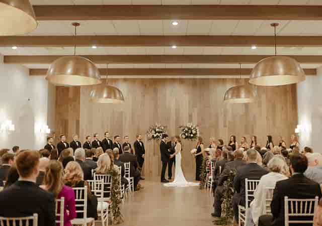 Elegant wedding ceremony at The Hall on Dragon with rustic wooden walls and floral decor.