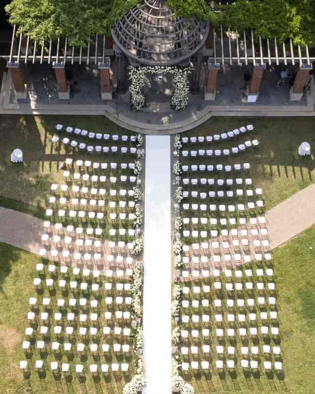 Outdoor wedding setup in Arlington Hall's Formal Garden with white chairs and floral decor.