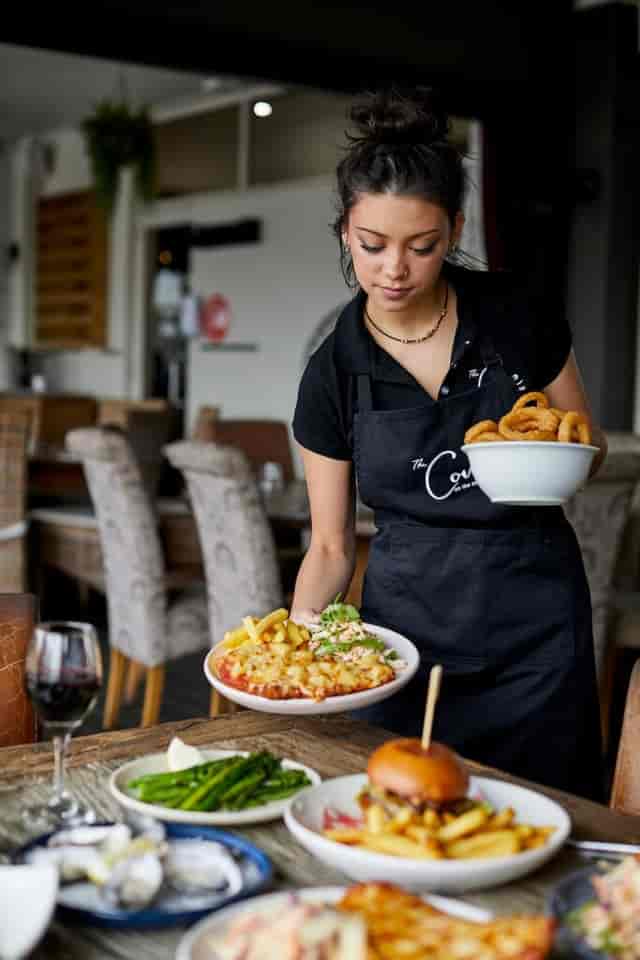 Service professional delivering elegantly presented food at Bistro, The Cove Hotel, for events.