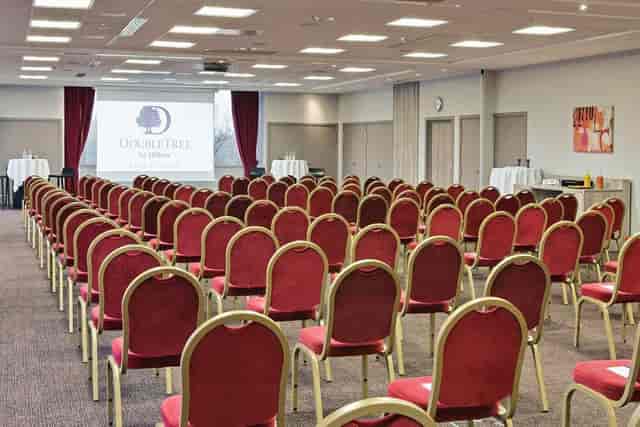 Function room at DoubleTree Lyon, red chairs set for a corporate conference event.