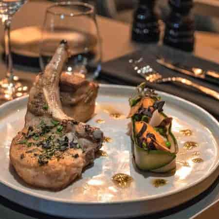 Plated pork chop with vegetables at Le Bistrot, ideal for upscale events and dining.
