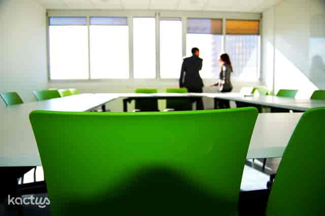 Modern meeting room with green chairs, ideal for productive workshops and discussions.