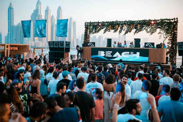 Vibrant beach party at Beach by FIVE, featuring an urban skyline and energetic crowd.